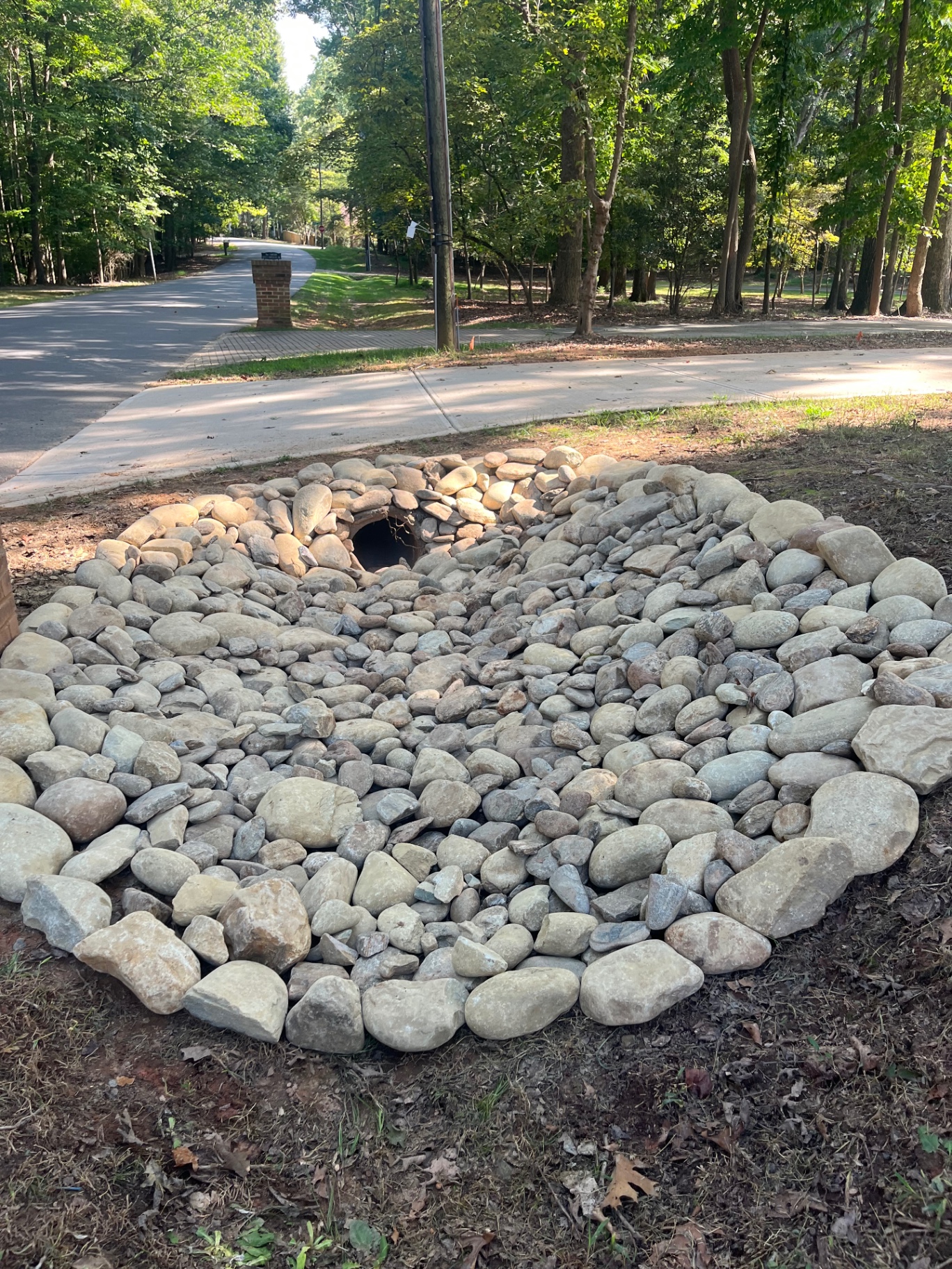 Culvert pipe outlet protected with a large river-rock apron at the edge of a roadside ditch in Lincolnton, NC