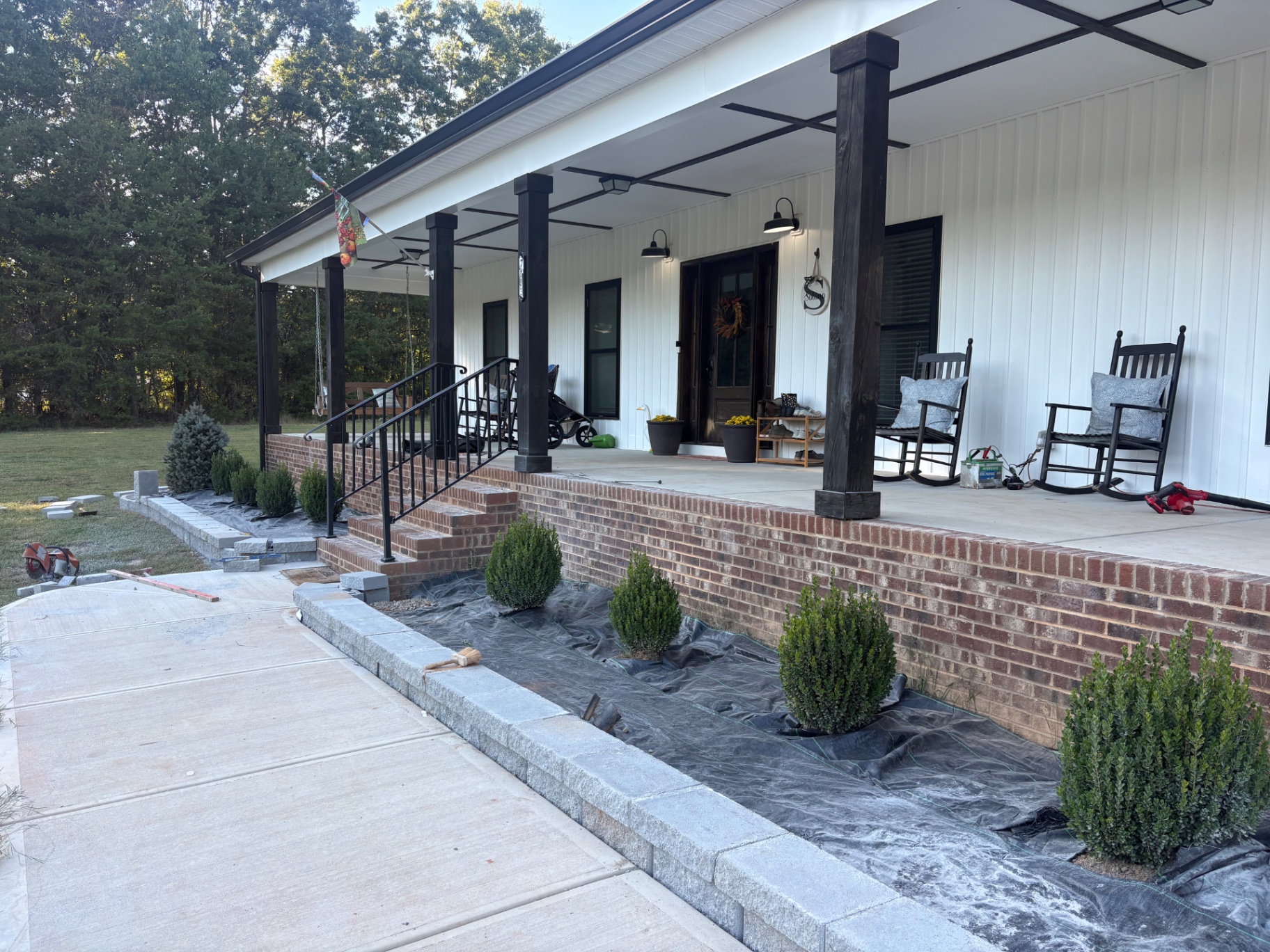 Block retaining wall edging new planting beds beside a front walkway during installation at a residential property